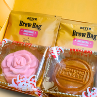 A gift box set featuring two packets of BETTR Coffee's Daybreak Brew Bag and two packaged mooncakes from Mdm Ling Bakery: a pink rose-shaped mooncake and a round traditional baked mooncake.